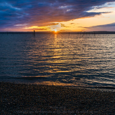 Last minutes of sunset over the lake with vibrant clouds, brings tranquility.